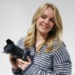 A female fashion photography student in a studio, holding a camera.