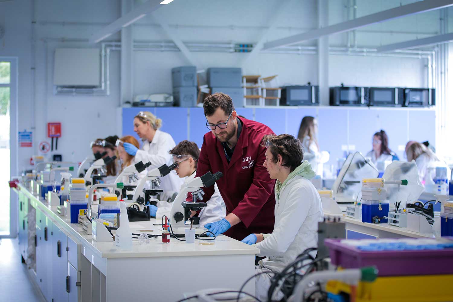 A lecturer helps students with a science experiment in the lab