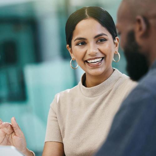 Smiling business woman talking to a male colleague in an office environment