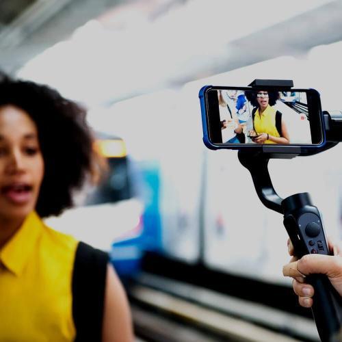 Young woman being filmed by a smartphone on a selfie stick