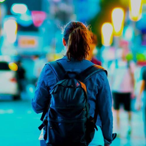 Woman with travelling backpack in city with neon lights