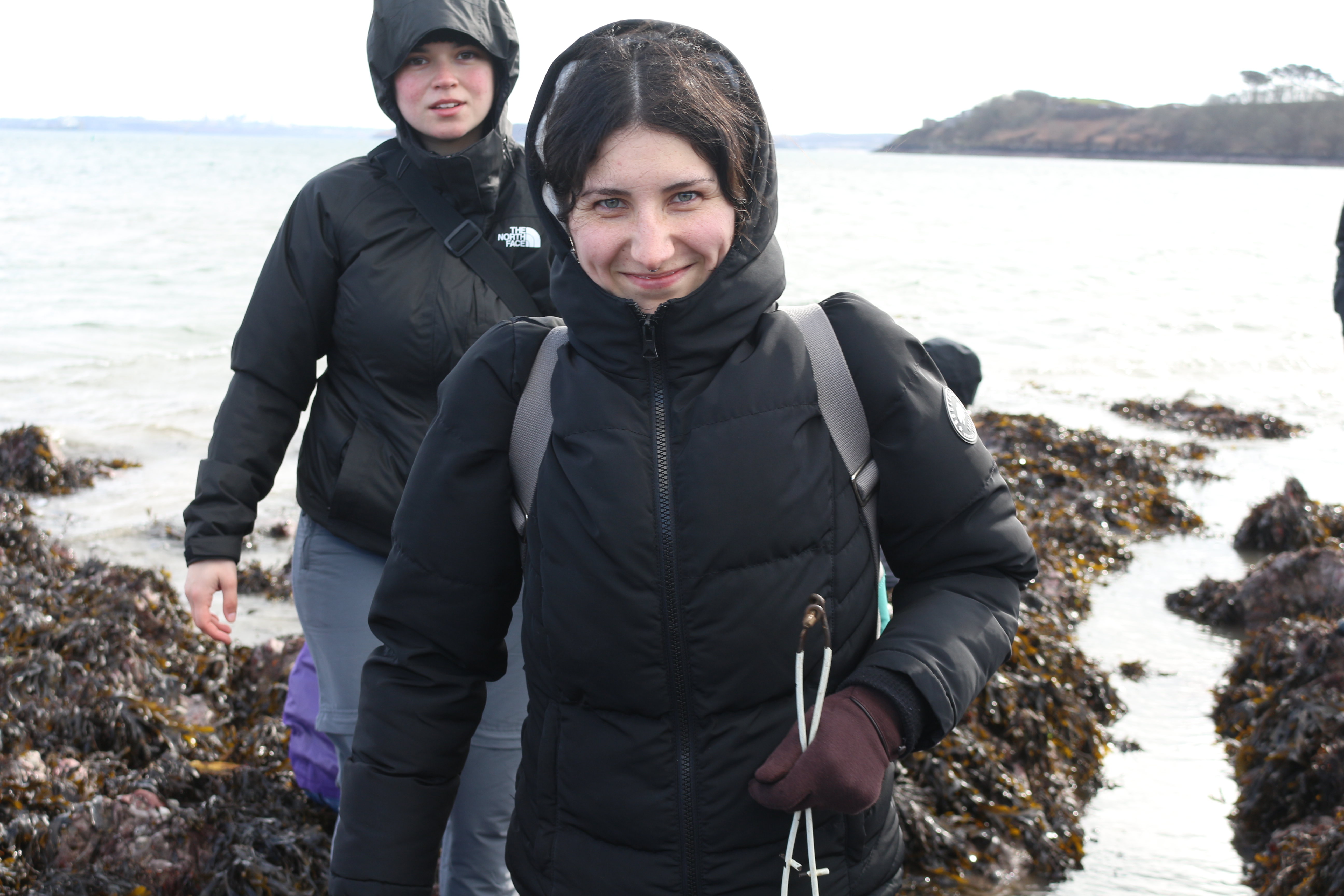 Two students walk towards the camera while wearing waterproof outdoor clothing