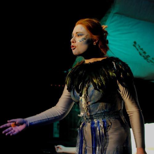 Student on stage performing in a feathered costume