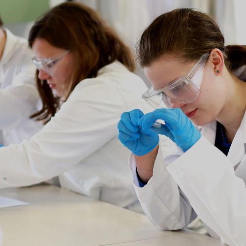 Students in lab wearing protective coats and goggles