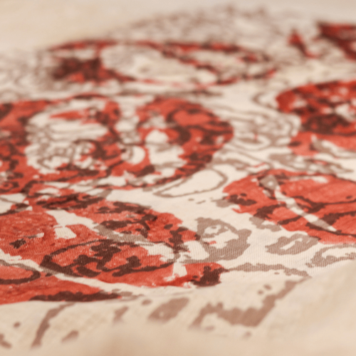 A photo of a piece of fabric with red and brown designs printed on top in ink.