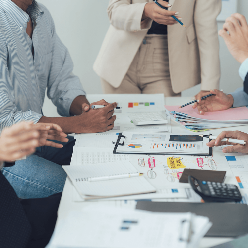 A group of coworkers sit around a table discussing strategies