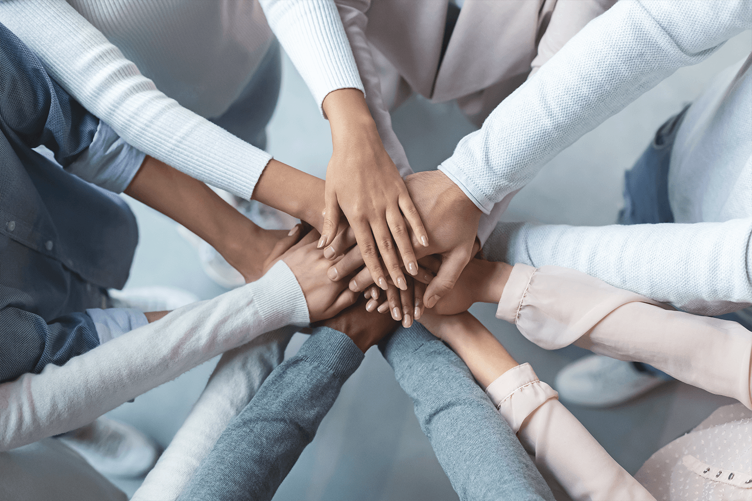 Five coworkers put their hands in the middle