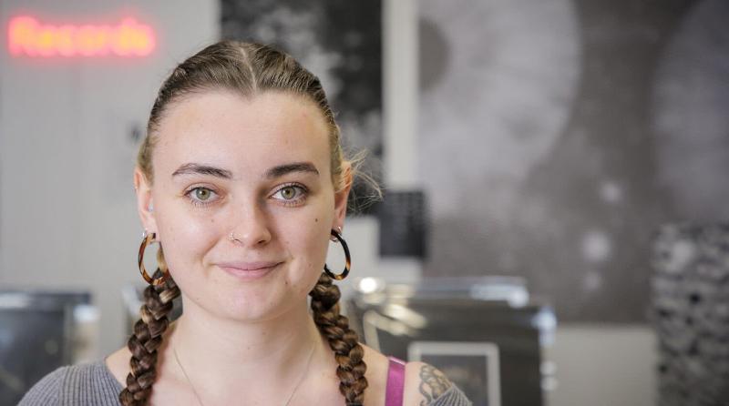 Student looks confidently at the camera with their monochromatic exhibition stand behind them