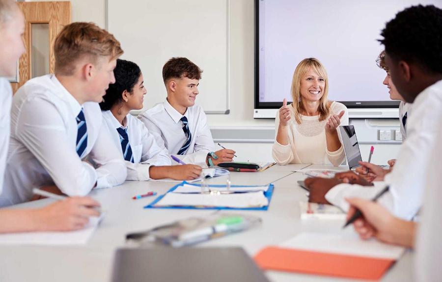 Teacher sitting around a table with Secondary school students