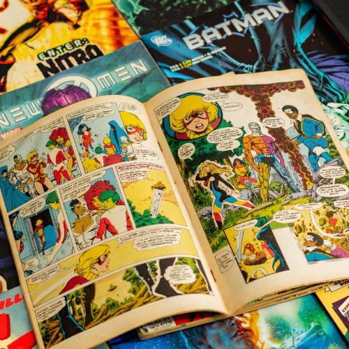 A comic book opened in front of a number of title pages