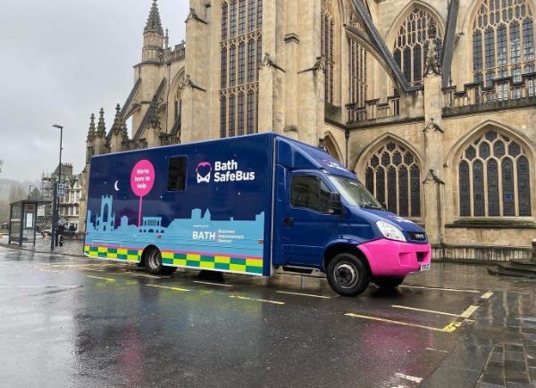 The Bath Safe Bus, decorated with images of the Bath skyscape, situated in front of the Bath Abbey 