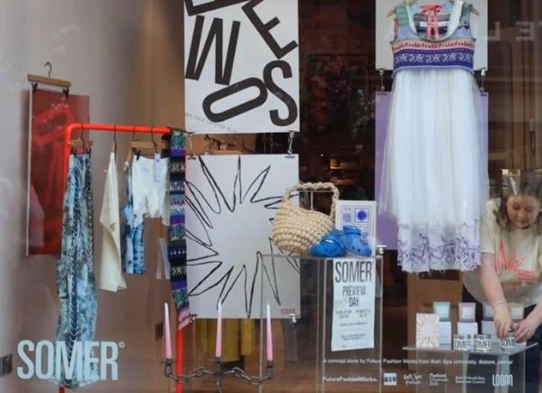 The front of a clothing store, with posters and clothes in the window