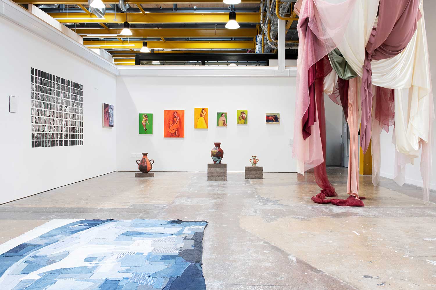 A wide, open exhibition space displaying ceramics and fabric pieces
