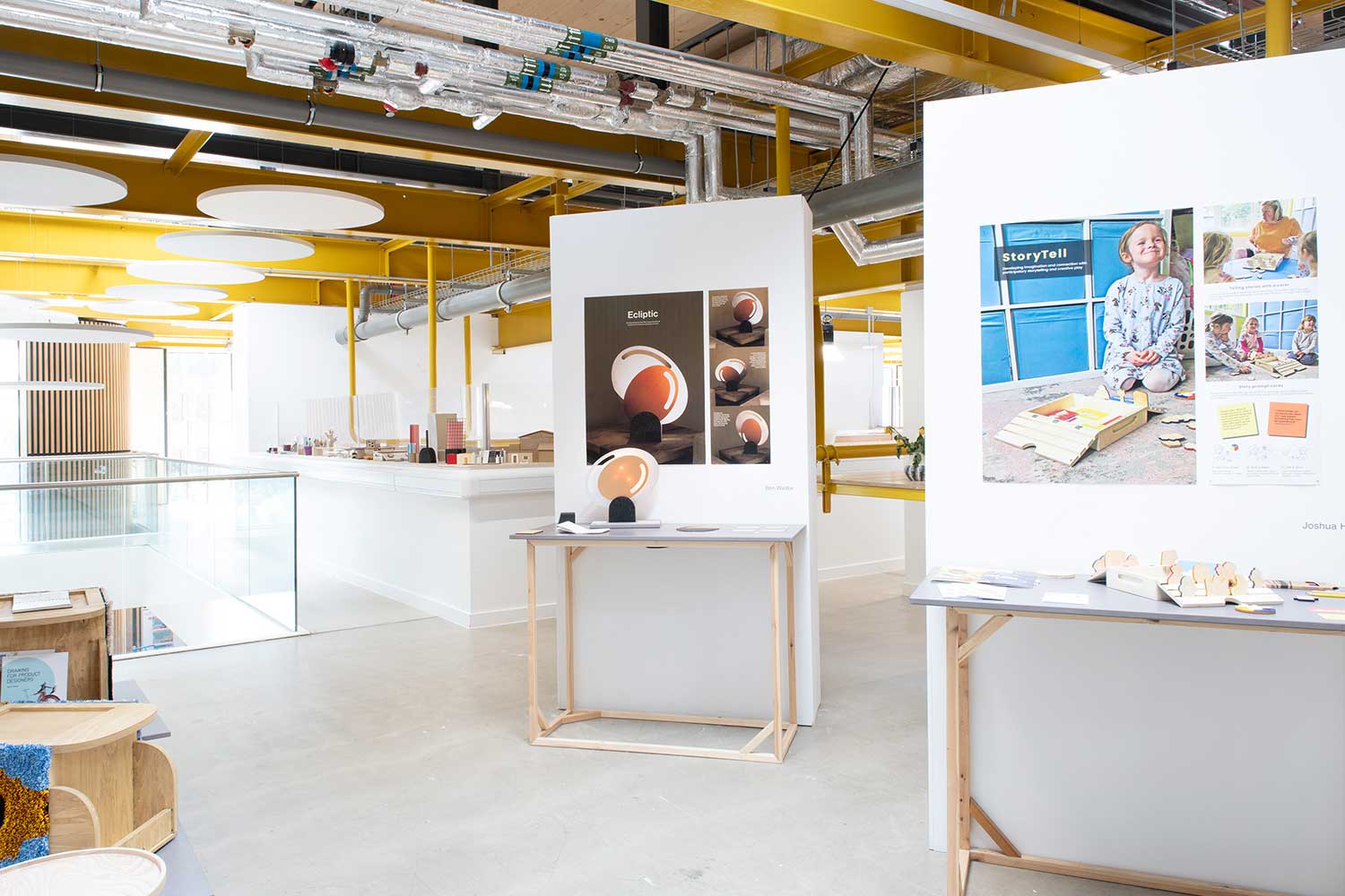 A wide, open exhibition space displaying product design prototypes and sketches