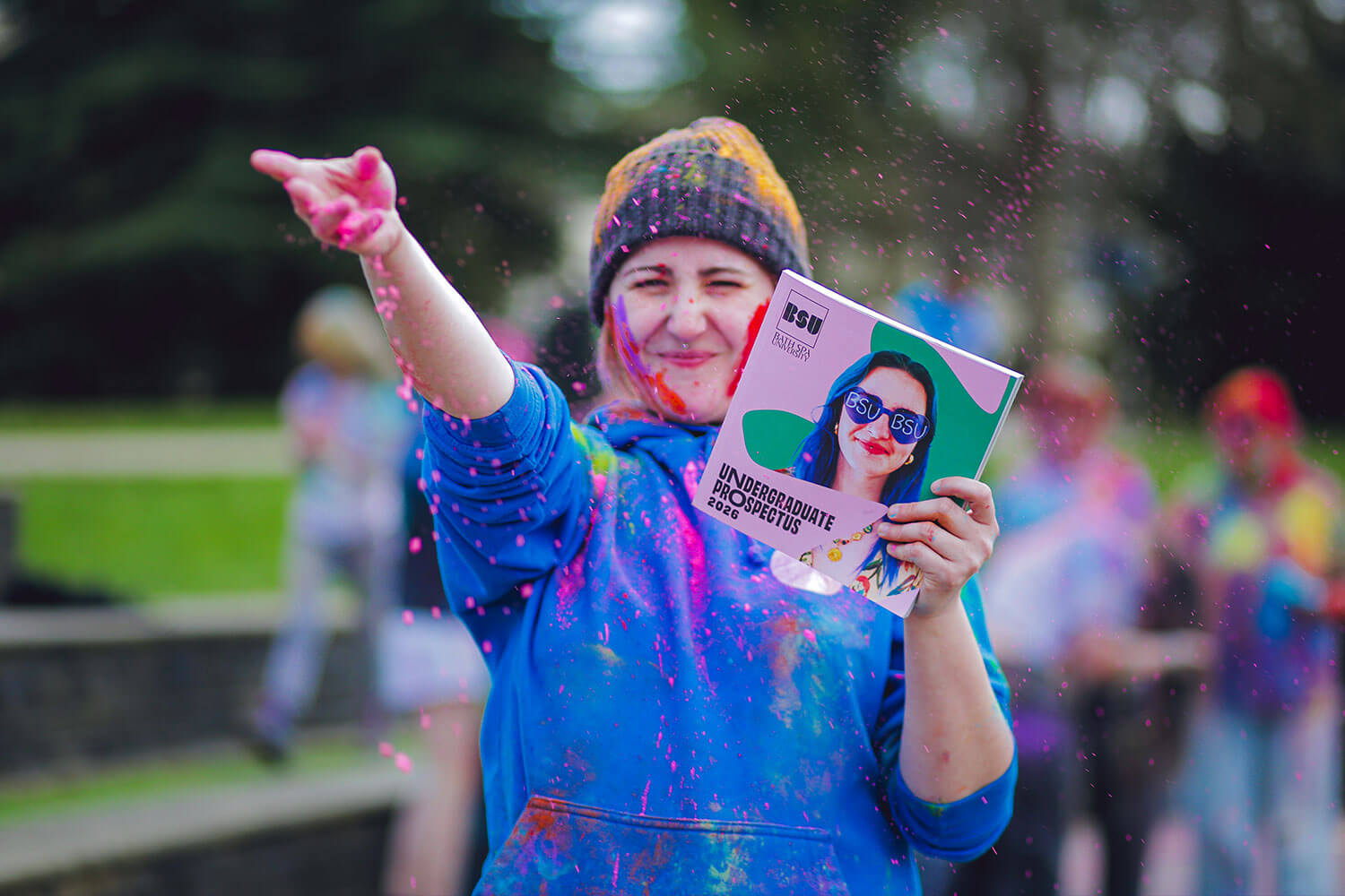A student holding up a colourful prospectus cover