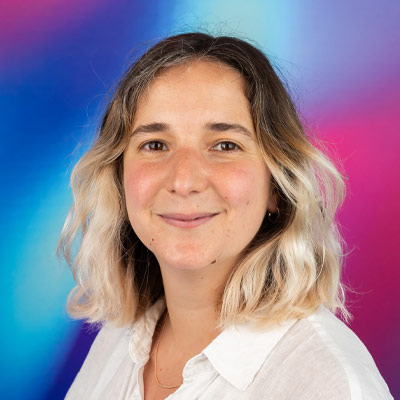 Person with long light hair wearing white shirt smiling at camera