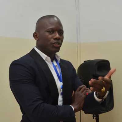 A person wearing a suit and tie presents at the front of a room