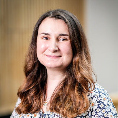 Headshot of person in pattern clothing with long light brown hair smiling
