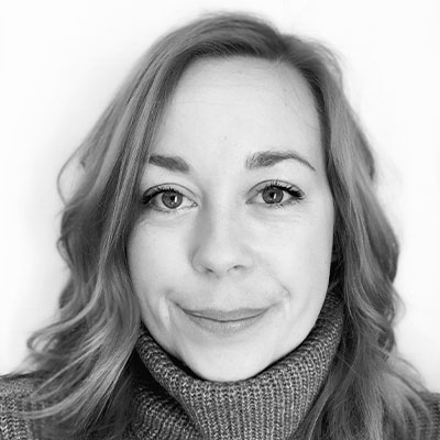 Close-up black and white headshot of someone with long light hair smiling