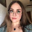 A person wearing gold glasses takes a selfie