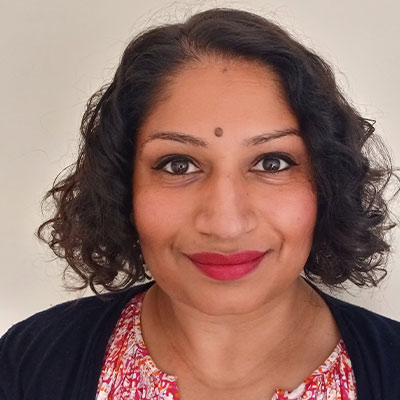 Headshot of someone smiling with shoulder length curly dark hair