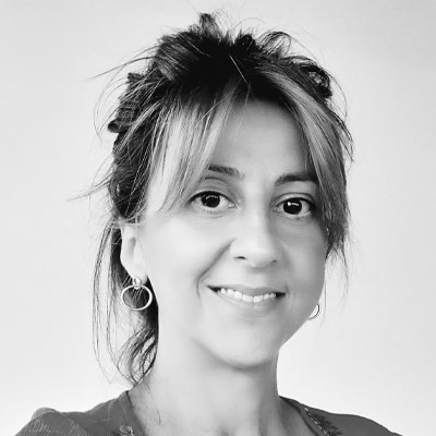 Headshot of someone in dark top with dark hair piled on head smiling