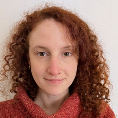 Person with long curly red hair wearing russet rollneck jumper