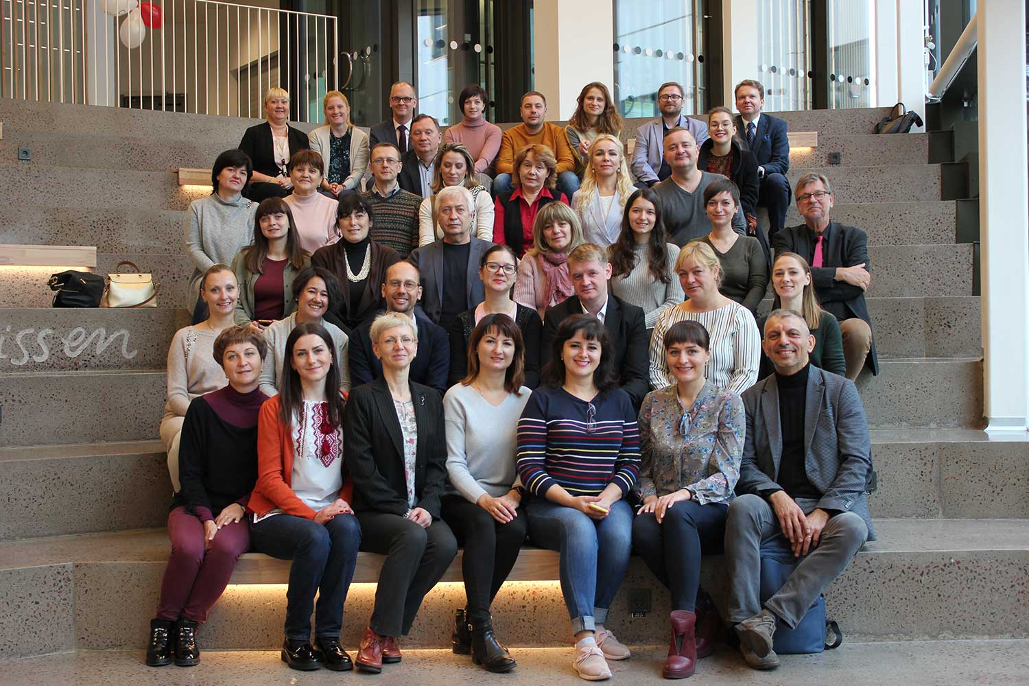 A large group of academics sit on the steps for a group photo