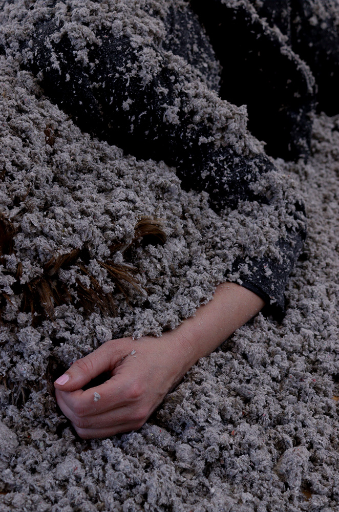 A person lies beneath a pile of dust