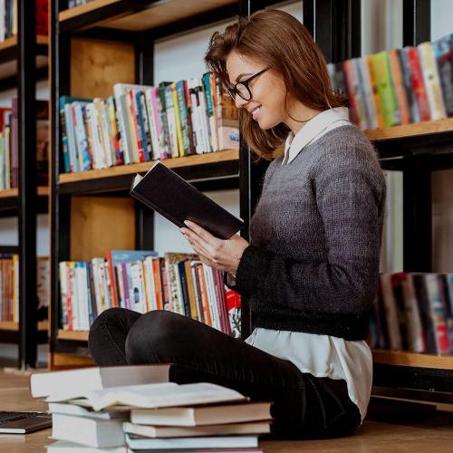 Woman sat in front of bookcase reading
