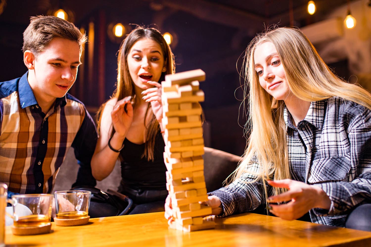 Three young people playing jenga board game